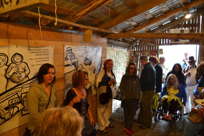 Photo of people viewing the Najawa installation at Bread & Puppet's Woodshed Gallery. The artists are shown presenting the artwork.