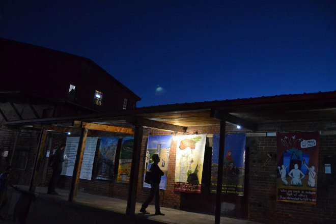 Night time photo of a person viewing the "Think of Others" exhibit at Art Hop.