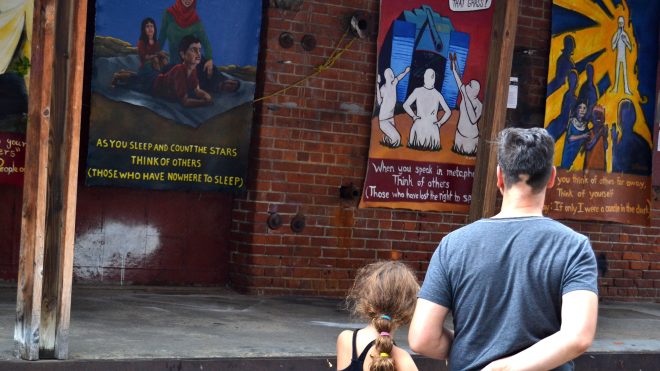 Photo of a father and child viewing the "Think of Others" exhibit at Art Hop.